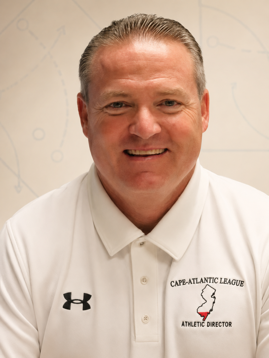 Portrait of Mike Gatley, founder of Next Level Consulting, wearing a white Cape-Atlantic League athletic director polo in front of faint play diagrams